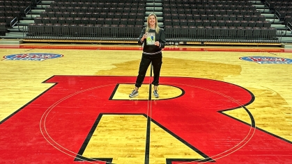 Lauren Sisler holding her memoir Shatterproof on court at Jersey Mike's Arena