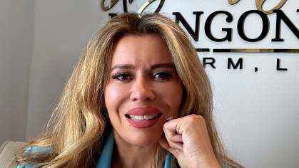 woman with long hair in bright blue blazer smiling with hand to chin