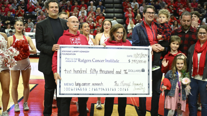 From left, Mark and Shelley Lampf presenting a check to the Rutgers Cancer Institute in memory of their daughter Stefanie at a Rutgers men’s basketball game. To Shelley’s left is Stefanie’s husband, Daniel, and their three children, her brother Sean, and sister Carolyn. To Mark’s right is Missak Haigentz Jr., a professor of medicine and leader of the lung cancer program at the Rutgers Cancer Institute.