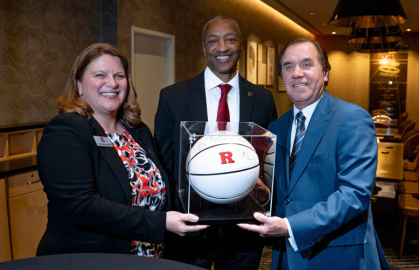 Francine Newsome Pfeiffer, senior vice president for Rutgers Government Relations, and Tate presented Coughlin with a basketball signed by Coach Steve Pikiell.