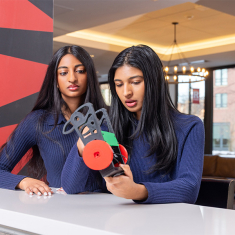 Naomi George watches sister Maria George work on Tera-Bite, her group’s combat robot prototype.